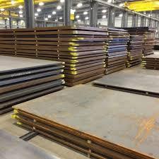 Stacked heavy steel plates stored in factory warehouse for fabrication
